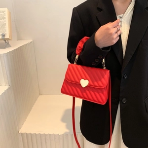 Detail der roten gesteppten Kunstlederhandtasche mit goldenem Herzverschluss und Tragegriff