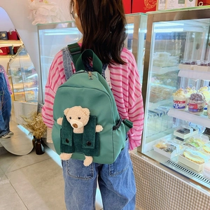 Zaino per bambini verde scuro in nylon con orsetto 3D indossato in una pasticceria