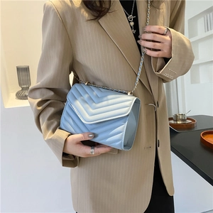 Light blue V-quilted leather crossbody bag with golden chain strap worn by a model