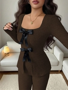 Detail eines zweiteiligen Stricksets mit eckigem Ausschnitt und schwarzen Satinschleifen