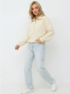 Cream half-zip sweatshirt paired with high-waisted blue jeans and white sneakers