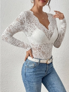 Dettaglio di elegante body in pizzo floreale bianco con scollo a V e maniche lunghe