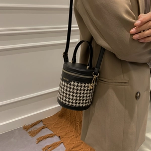 Mini houndstooth bucket bag with leather trim and gold logo shown on model