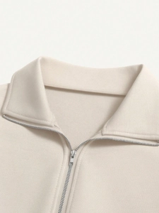 Detail of cream half-zip sweatshirt featuring silver metal zipper and knit collar texture
