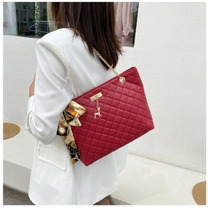 Red quilted shoulder bag with gold chain strap and silk scarf detail on white blazer
