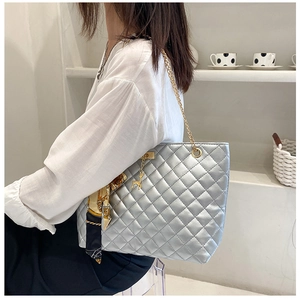 Detail of silver quilted shoulder bag featuring gold chain strap and elegant silk scarf