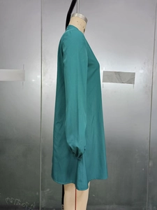 Detail view showing the sleek teal long-sleeve dress fabric and tailored A-line side cut