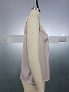 Detail view of smooth champagne satin sleeveless top texture on a display mannequin