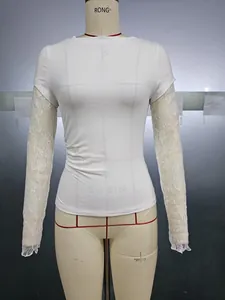 Detail view of women's white slim-fit top featuring floral lace patchwork on long sleeves