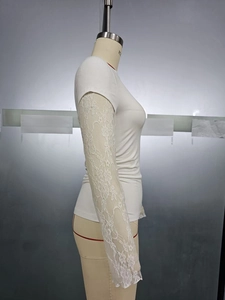 Detail of elegant white lace floral stitching on sleeves of a slim-fit crewneck top