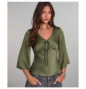 Detail of dark green satin blouse showing V-neckline with chic bow tie decoration