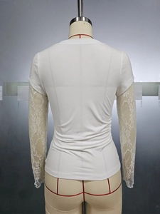 Detail view showing white long-sleeve top with floral lace patchwork sleeves on mannequin