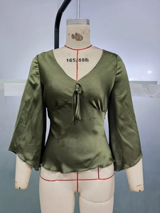 Detail of olive green satin blouse with deep V-neck, neck ties and flared bell sleeves