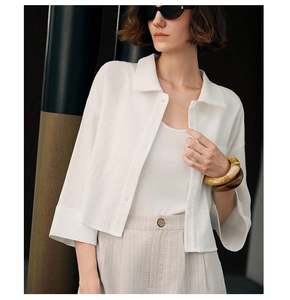 Detailed texture of white cotton long-sleeve shirt with amber resin bangles and neutral pants