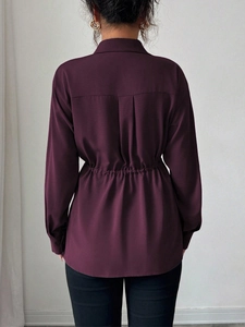 Détail de la blouse bordeaux avec taille cintrée au dos et texture élégante du tissu