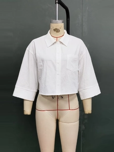 Close-up of white cropped cotton shirt with classic collar and textured fabric detail