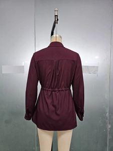 Détail d'une chemise bordeaux à manches longues avec cordon à la taille et pli dans le dos