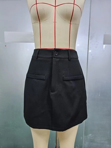 Detail of high waisted black mini skirt featuring a single button and decorative pockets