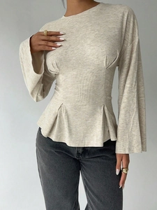 Detail of light beige knit peplum top with flared sleeves and textured ribbed fabric
