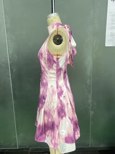 Dettaglio dell'abito tie-dye viola con collo alto e grande fiocco decorativo sul retro