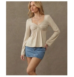 Detail of the sweetheart neckline and elegant twist-knot design on the beige long sleeve top