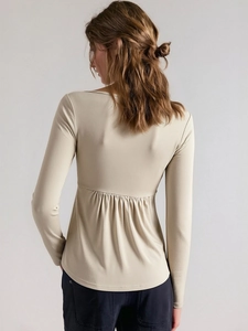 Women's long sleeve cream top featuring a unique ruched detail on the lower back