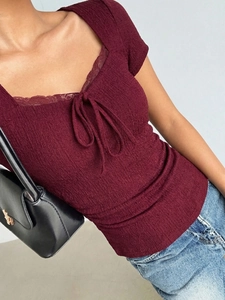 Close-up of burgundy square neck top with lace trim, bow tie, and textured fabric