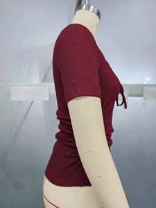 Detailed close-up of burgundy smocked fabric texture and front lace-up tie on the slim top