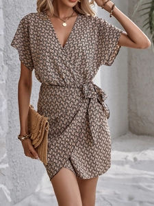 Détail de la robe portefeuille avec col en V, lien à la taille et imprimé de chaînes