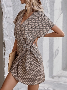 Détail d'une robe fleurie à manches courtes avec col en V croisé et ceinture nouée