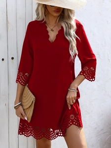 Detail of scalloped V-neckline and laser-cut floral patterns on a dark red dress