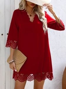 Detail of scalloped V-neckline and intricate laser-cut eyelet floral pattern on red dress