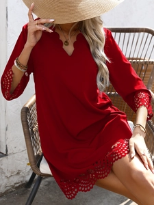 Detail of red summer dress featuring laser-cut floral patterns and scalloped V-neckline