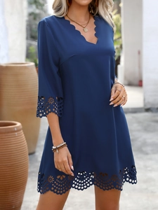 Detail of navy blue V-neck dress featuring scalloped edges and laser-cut floral patterns
