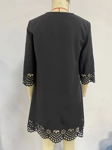 Detailed back view of a black midi dress featuring laser-cut floral patterns on hem