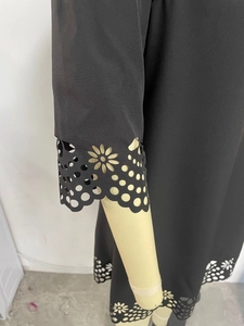 Detailed view of the intricate laser-cut hollow daisy patterns on the black dress hem