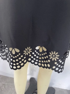 Detailed close-up of laser-cut floral patterns and geometric dots on a black A-line dress