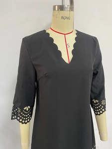 Detail of scalloped V-neckline and laser-cut floral embroidery on a black dress