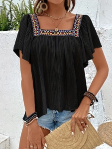 Close-up of colorful geometric embroidery on a black square neck summer boho blouse