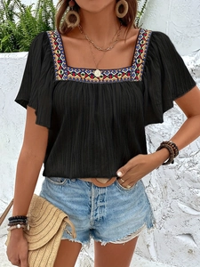 Detailed view of bohemian square neck embroidery on black ruffled cotton blouse for summer