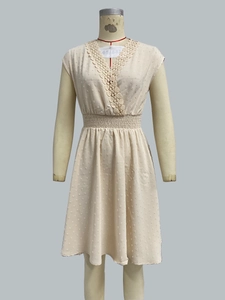 Detail of V-neck crochet lace and swiss dot textured fabric on a beige sleeveless dress