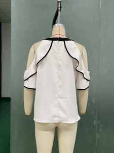 Detail view of white off-the-shoulder shirt back with black contrast ruffles and layers