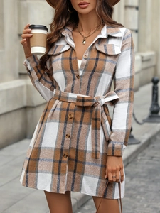 Detail of plaid long sleeve dress featuring front buttons, dual chest pockets and waist belt