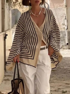 Outdoor street shot of a woman in a striped V-neck cardigan with a chic chain necklace