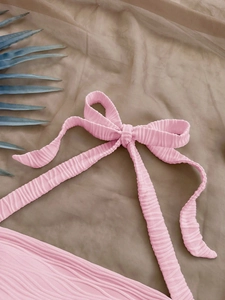 Pink ribbed tie-front crop top with decorative bow and beach vacation aesthetic texture
