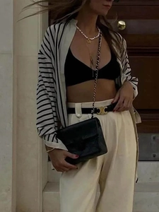 Detail of a black and white striped long sleeve cardigan with a chic chain handbag