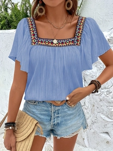 Detail of bohemian square neck blouse with colorful geometric embroidery and pleated texture