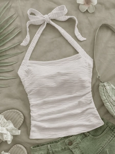 Flat lay of cream halter top with wavy pleat texture and neck tie bow detail