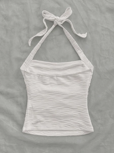 Macro shot of white halter neck top featuring textured wave pattern fabric and neck ties