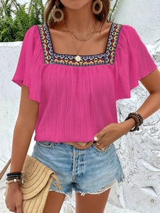 Detail of rose pink square neck blouse featuring colorful geometric embroidery and ruffle sleeves